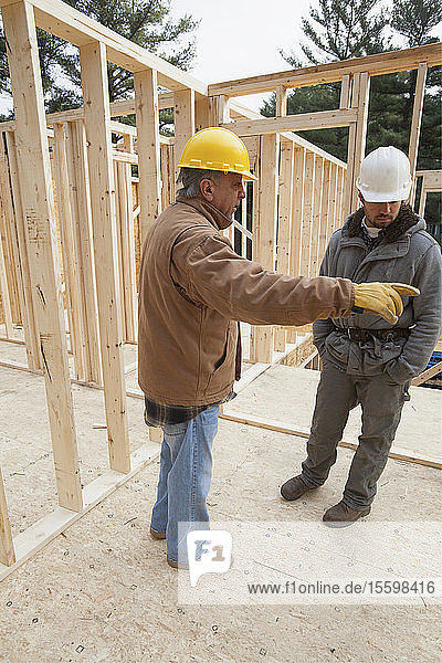 Ein Bauleiter bespricht den Bau eines Hauses mit einem Zimmerer