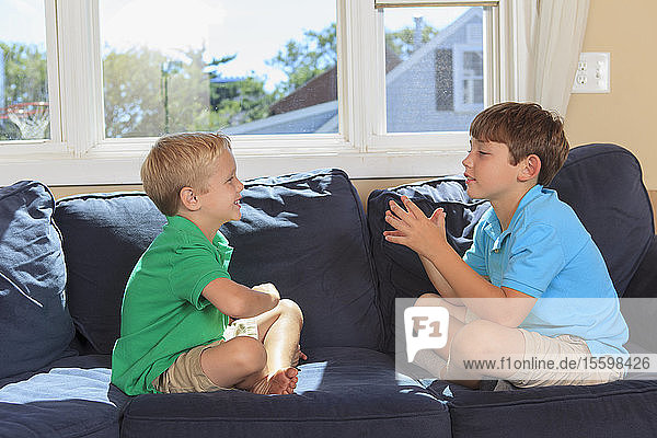 Hörgeschädigte Jungen spielen und gebärden in amerikanischer Zeichensprache auf ihrer Couch