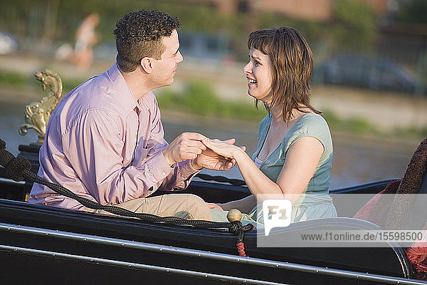 Ein mittelgroßer Mann bietet einer mittelgroßen Frau in einer Gondel einen Ehering an