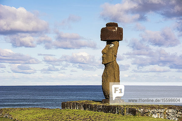 Ein einzelner Moai vor einem blauen Hintergrund aus Himmel  Wolken und Meer; Osterinsel  Chile