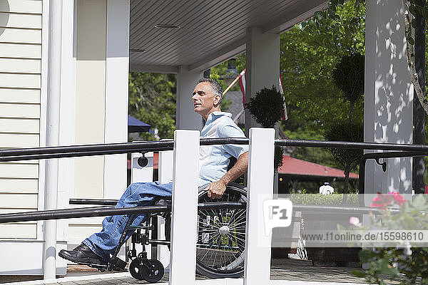 Mann mit Querschnittslähmung im Rollstuhl an der Spitze einer begehbaren Rampe
