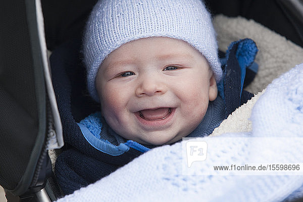 8 Monate altes Baby lächelnd in einem Kinderwagen