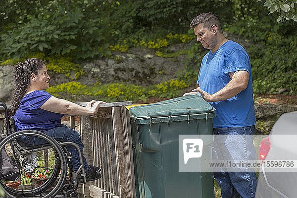 Frau mit Spina Bifida und ihr Mann bringen den Müll raus