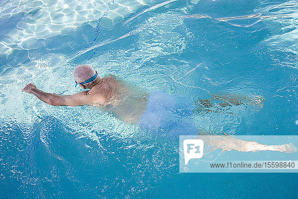 Rear view of a senior man swimming in a swimming pool