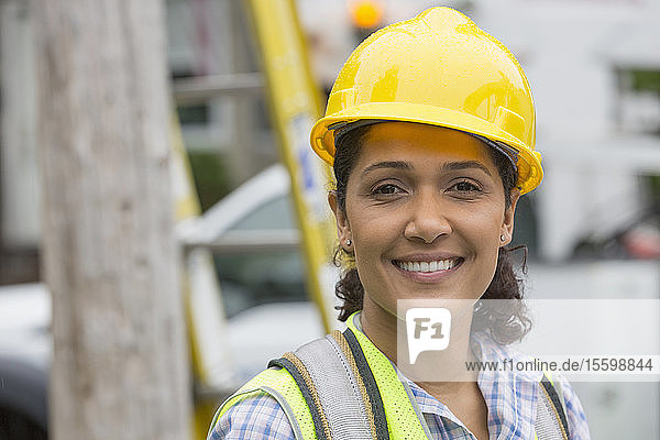 Porträt einer glücklichen hispanischen Mitarbeiterin eines Versorgungsunternehmens  die lächelt