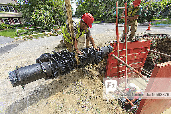 Bauarbeiter bei den Vorbereitungen zum Absenken eines Wasserleitungsabschnitts