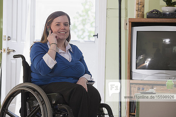 Frau mit Spina Bifida im Rollstuhl telefoniert mit einem Mobiltelefon