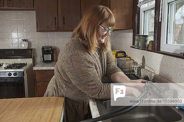 Eine blinde Frau schließt den tragbaren Geschirrspüler in ihrer Küche an