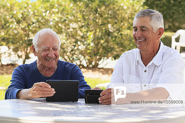 Älterer  sehbehinderter Vater und älterer Sohn bei der Nutzung elektronischer Hilfsmittel