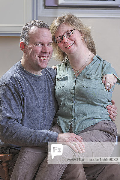 Frau mit TAR-Syndrom sitzt auf dem Schoß ihres Mannes