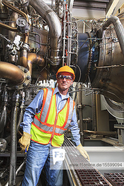 Engineer at fuel injection stage of gas turbine which drives generators in power plant while turbine is powered down