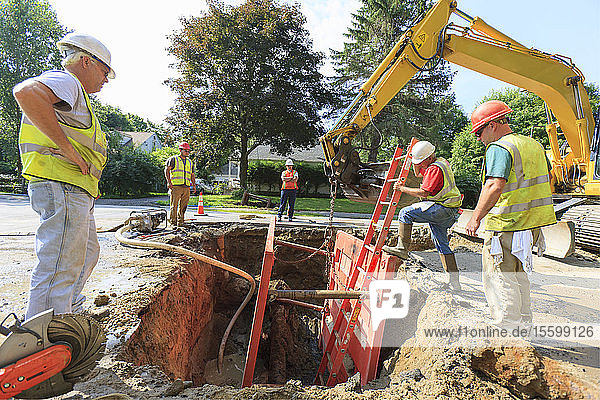 Bauarbeiter betritt Verbau  um Wasserleitung zu inspizieren