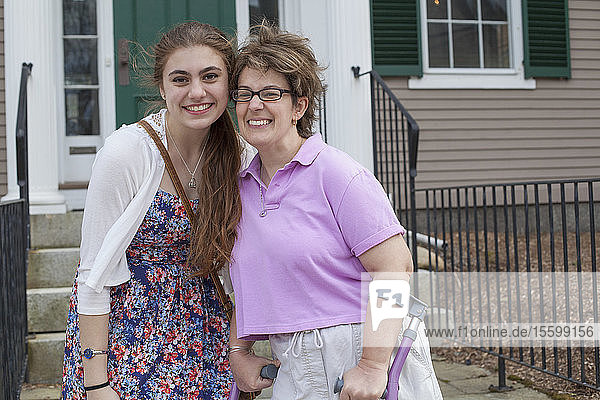 Frau mit zerebraler Lähmung vor einem Haus mit ihrer Schwester