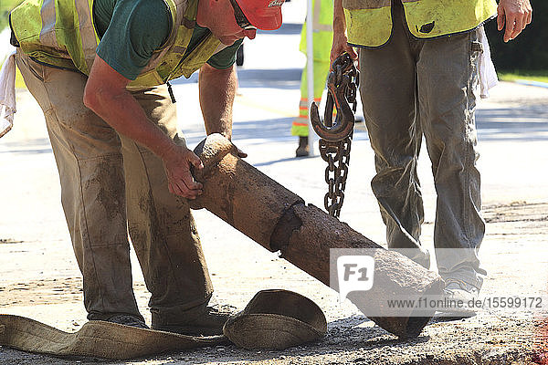 Bauarbeiter inspizieren einen verrosteten Wasserleitungsabschnitt
