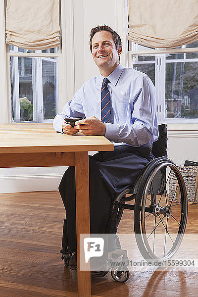 Geschäftsmann mit Querschnittslähmung im Rollstuhl  der ein Smartphone benutzt