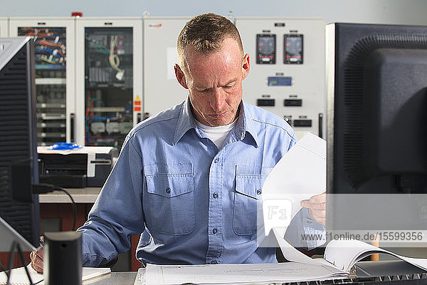 Elektroingenieur bei der Überprüfung von Protokollen im zentralen Betriebsraum eines Kraftwerks