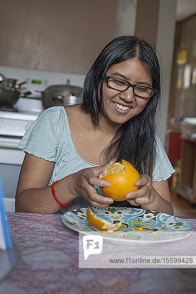 Frau mit Sehbehinderung schält eine Orange