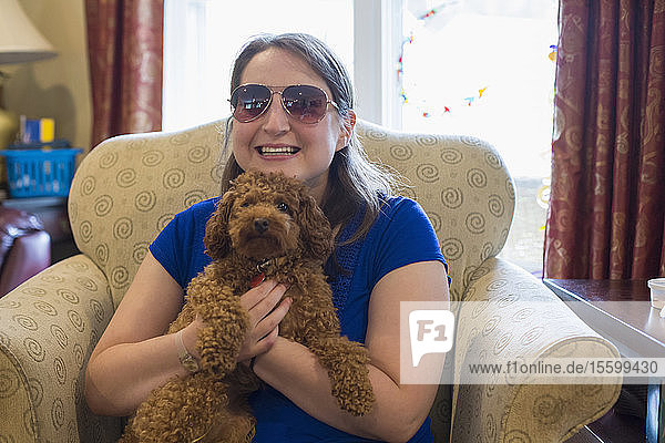 Junge Frau mit zerebraler Lähmung spielt zu Hause mit Hund