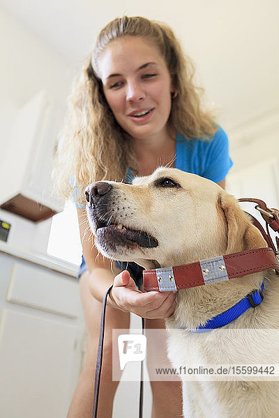 Frau mit Sehbehinderung legt ihrem Diensthund den Gurt an