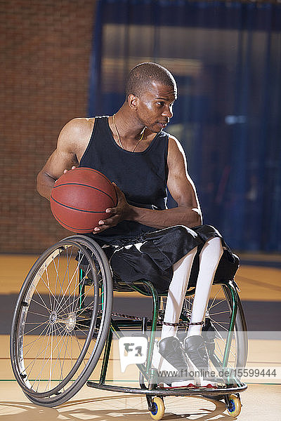 Mann mit Spinaler Meningitis sitzt im Rollstuhl und spielt Basketball