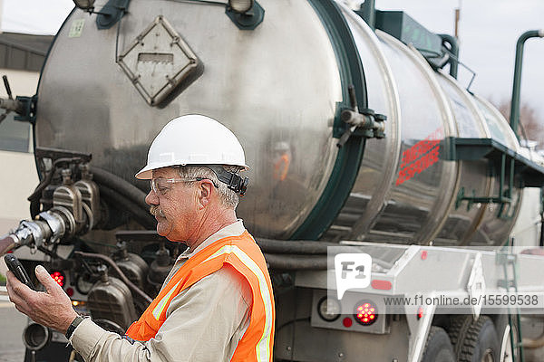 Umwelttechniker telefoniert mit Tankwagen bei der Beseitigung von Sondermüll