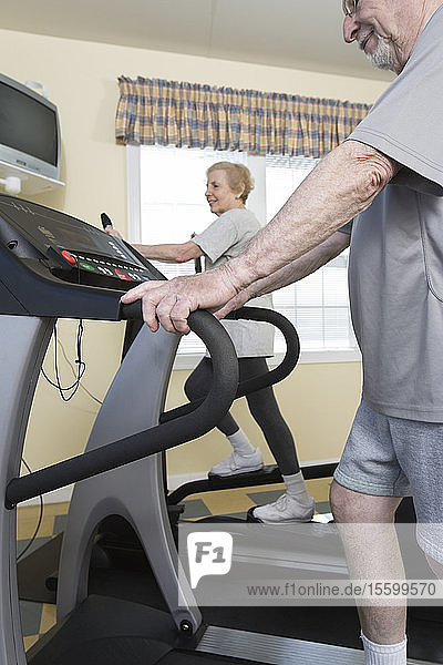 Älteres Ehepaar beim Laufen auf dem Laufband im Fitnessstudio.