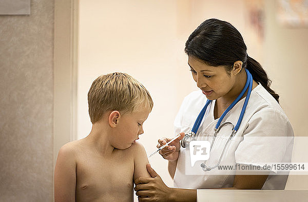 Ärztin verabreicht ihrer jungen Patientin einen Impfstoff.