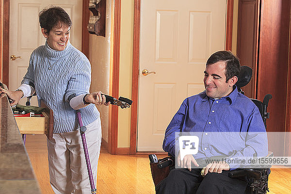 Frau mit Cerebralparese benutzt Krücken und gibt ihrem Mann im Rollstuhl mit Cerebralparese einen Dosenöffner
