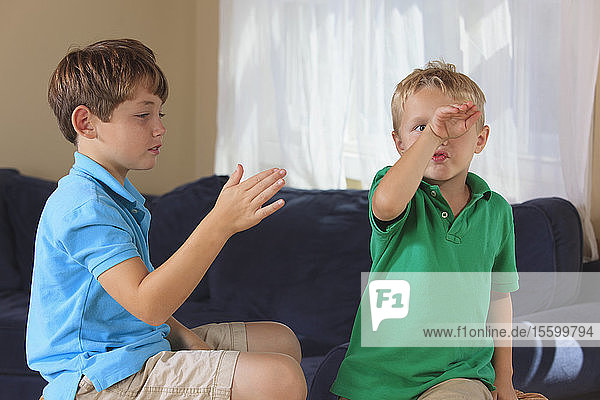Boys with hearing impairments signing in American sign language on their couch