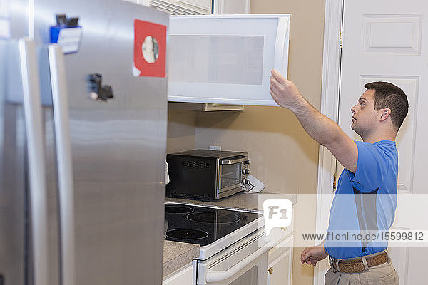 Mann mit Down-Syndrom öffnet Schublade in der Küche