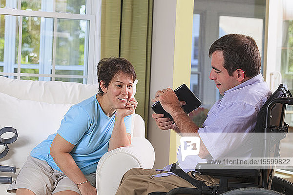 Ehepaar mit Cerebralparese schaut auf ein digitales Tablet