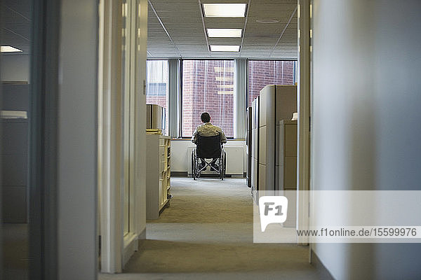 Rückansicht eines im Rollstuhl sitzenden Mannes in einem Büro