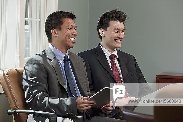 Zwei Geschäftsleute benutzen ein elektronisches Pad in einem Sitzungssaal
