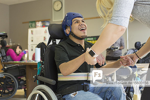 Junge mit spastischer Tetraplegie und Zerebralparese benutzt seinen Helm und den Gurt