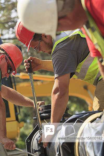 Bauarbeiter verwenden einen Drehmomentschlüssel  um den Abschnitt der Wasserleitung mit Schrauben zu sichern
