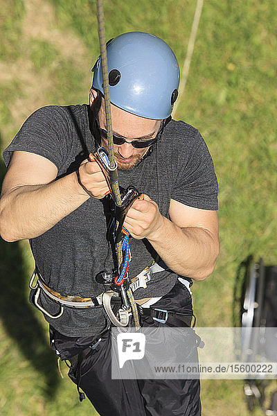 Man with spinal cord injury using adaptive climbing equipment for rock climbing