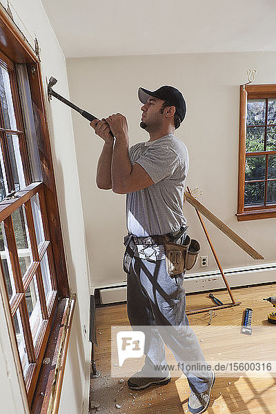 Spanischer Zimmermann entfernt Fensterrahmen aus einem Raum im Haus
