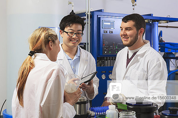 Studenten der Ingenieurwissenschaften untersuchen Flüssigkeitsbehälter und diskutieren in einem Raum mit einem Wasser-Ultra-Reinigungssystem in einem Labor