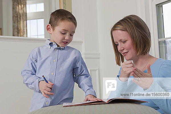 Woman signing the word 'Draw' in American Sign Language while teaching her son