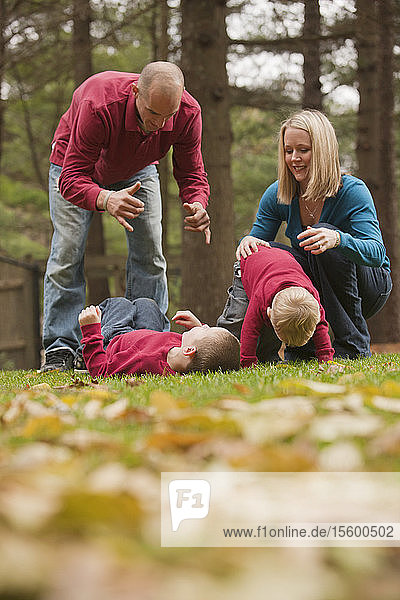 Ein Mann gebärdet das Wort Play in amerikanischer Gebärdensprache  während er mit seinem Sohn in einem Park spielt