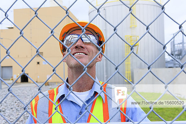 Engineer at electric power plant inside secured fence looking at power plant buildings
