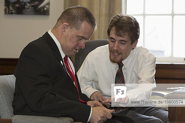 Man with Down Syndrome working as a Legislative Assistant using a tablet with his colleague in the State Capitol office