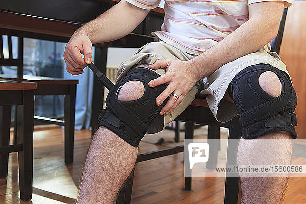 Man adjusting braces on his knees after anterior cruciate ligament (ACL) surgery