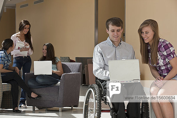 Lehrer mit Rückenmarksverletzung und Schüler arbeiten an einem Laptop