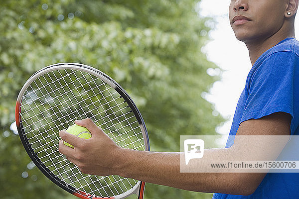 Halbansicht eines Teenagers  der einen Tennisschläger und einen Tennisball hält