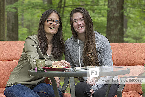 Glückliche Frau mit Multipler Sklerose sitzt mit ihrer Tochter zusammen