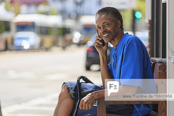 Man with Traumatic Brain Injury waiting at the bus terminal while on his phone