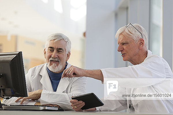 Two doctors discussing information on a computer and a tablet  one with Muscular Dystrophy