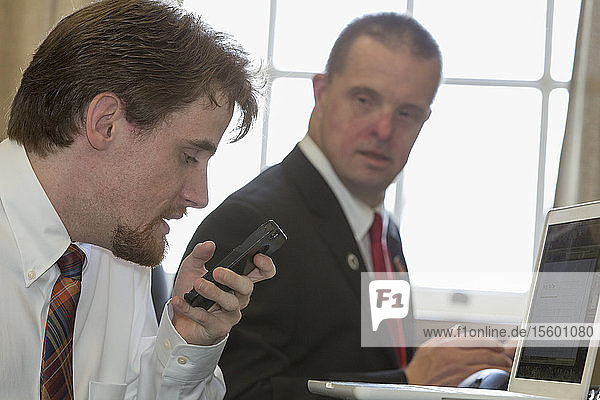 Man with Down Syndrome working with a collaborator using a phone in the State Capitol office