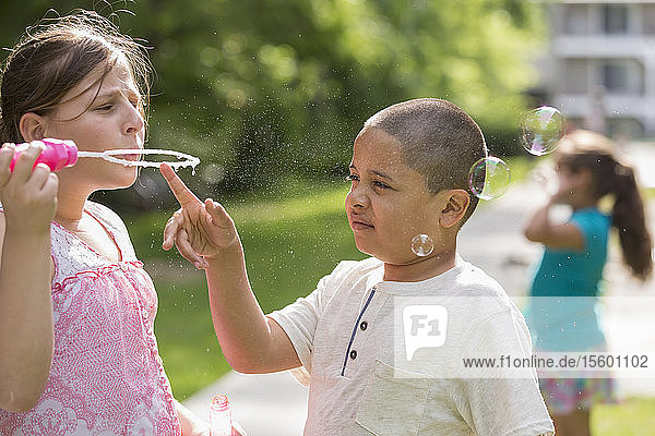 Hispanischer Junge mit Autismus spielt draußen mit seiner Schwester
